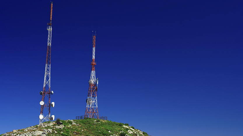 Telecommunication tower on the green field with blue sky